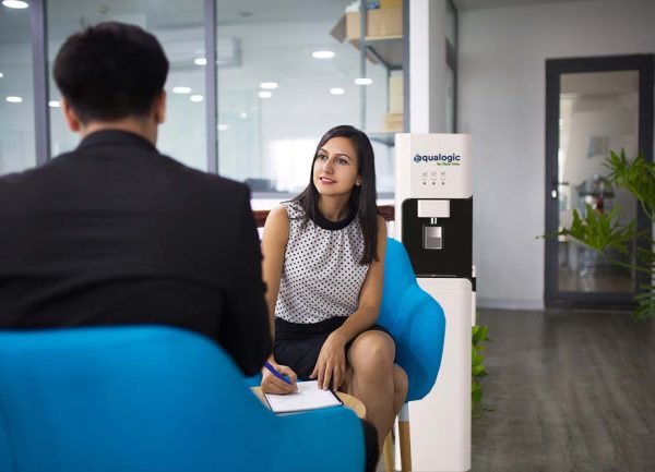 Portrait of smiling hr manager having interview with candidate. Young Caucasian businesswoman having meeting with businessman in lobby and writing after him. Meeting and job interview concept